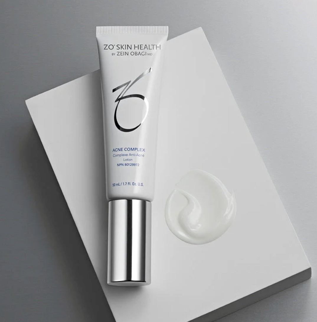 A tube of ZO Skin Health Acne Complex with a small amount of the cream product displayed in front of it.