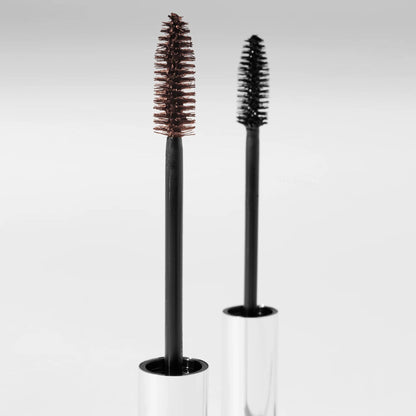 A black and brown serum mascara brushes with clear cylindrical holders on a light gray background