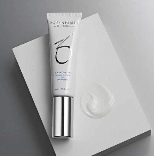 A tube of ZO Skin Health Acne Complex with a small amount of the cream product displayed in front of it.